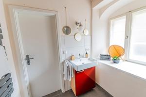 ein Bad mit einem roten Waschbecken und einem Fenster in der Unterkunft Pension zur Postmeile in Bad Belzig