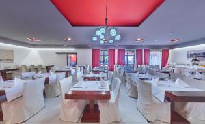 un restaurante con mesas y sillas blancas y una lámpara de araña en Hotel Villa Donat, en Sveti Filip i Jakov