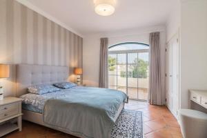 ein Schlafzimmer mit einem Bett und einem großen Fenster in der Unterkunft Moradia Geminada com 2 Quartos Quinta do Lago in Quinta do Lago