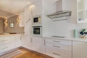 eine weiße Küche mit weißen Schränken und Geräten in der Unterkunft Moradia Geminada com 2 Quartos Quinta do Lago in Quinta do Lago