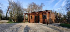a small wooden cabin on a gravel road at Kingfisher Cabin - Wild Escapes Wrenbury off grid glamping - ages 12 and over in Baddiley