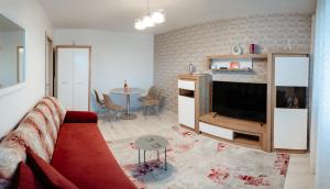 a living room with a red couch and a tv at Carla's Apart Palas-Hala Centrala 1 Bedroom, airport shuttle in Iaşi