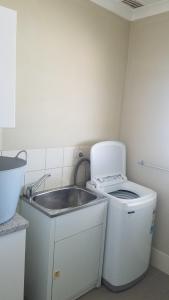 una pequeña cocina con fregadero y lavadora en Brockman Cottage Denham en Denham