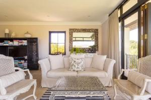 a living room with a white couch and chairs at Alphen Drive Apartments in Cape Town