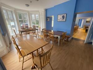 ein Esszimmer mit blauen Wänden, Holztischen und Stühlen in der Unterkunft Glendalough International Youth Hostel in Laragh