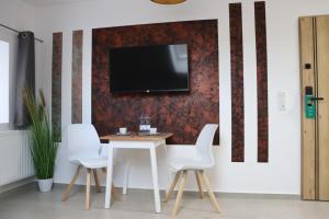 een tafel en stoelen met een tv aan de muur bij Apartments Morsum in Thedinghausen