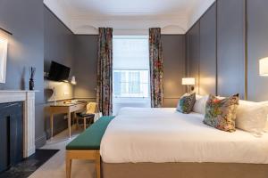 a bedroom with a bed with a fireplace and a desk at The Goodenough Hotel London in London