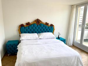 a bed with a blue headboard in a bedroom at Hawa Apartment - two balcony - by PA in Lucerne