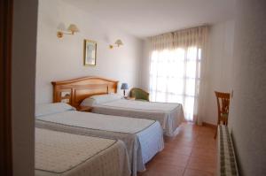 Habitación de hotel con 2 camas y ventana en Hotel El Gamo, en Tragacete
