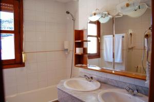 a bathroom with two sinks and a mirror and a tub at Hotel El Gamo in Tragacete