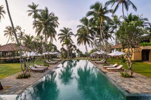 einen Pool in einem Resort mit Liegestühlen und Palmen in der Unterkunft Kayaam House in Tangalle