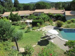 un jardin avec un parasol et une piscine dans l'établissement La Villa Les Hespérides, à Grimaud