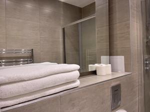 een badkamer met een spiegel en handdoeken op een plank bij Lovely 2 Double Bedroom Flat with free parking - At the Atrium MK in Milton Keynes