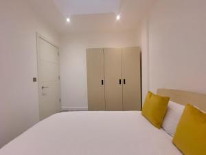 a bedroom with a large white bed with yellow pillows at Lovely 2 Double Bedroom Flat with free parking - At the Atrium MK in Milton Keynes