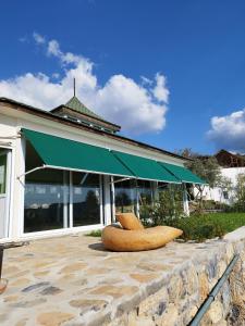 a building with a green awning and two chairs at Olive Garden Retreat in Milas