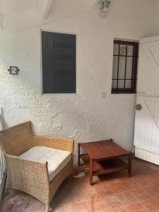 a room with a wicker chair and a table at Joli appartement entier sur jardin avec salle d'eau et chambre indépendantes et cuisine équipée in Marigot