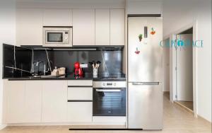uma cozinha branca com um frigorífico e um micro-ondas em AZAFRAN apartamento para descanso cerca de la playa em Calpe
