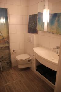 ein Bad mit einem WC, einem Waschbecken und einer Dusche in der Unterkunft Reetdach Friesenhof Süderende in Westerland