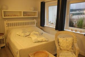 ein Schlafzimmer mit einem Bett, einem Stuhl und einem Fenster in der Unterkunft Reetdach Friesenhof Süderende in Westerland