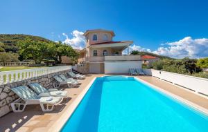 a swimming pool with chairs and a house at Apartments Dedić in Supetarska Draga