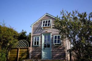 uma casa de madeira com uma porta azul e janelas em Tiny House on isolated farm by the Cornish Coast em Bude