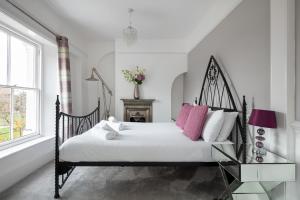 um quarto com uma cama preta e branca com almofadas cor-de-rosa em Castle Properties: The Duchess, 3 Bed Family cottage em Windsor