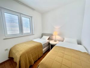 - 2 lits dans une petite chambre avec fenêtre dans l'établissement Apartment Golden View Dramalj, à Dramalj