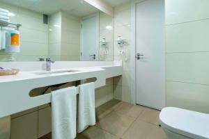 La salle de bains est pourvue d'un lavabo, de toilettes et d'un miroir. dans l'établissement Paradise Park Fun Lifestyle Hotel, à Los Cristianos