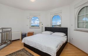 een slaapkamer met een bed met witte lakens en ramen bij Apartments Dedić in Supetarska Draga
