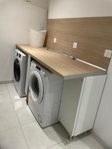 una lavanderia con bancone, lavatrice e asciugatrice di Chez Julie petit appartement une chambre rez jardin maison a Tulle