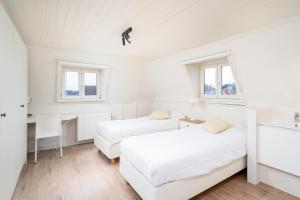 two beds in a white room with a desk and windows at CAPRINO Guesthouse in Knokke-Heist