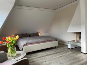 una camera con letto e vaso di fiori di Ferienwohnung-Weidenstieg-OG a Wenningstedt