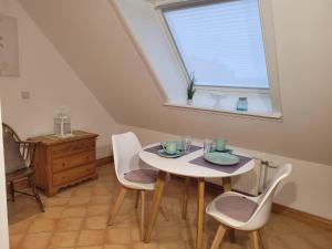 una sala da pranzo con tavolo, sedie e finestra di Ferienwohnung-Weidenstieg-OG a Wenningstedt