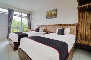 um quarto de hotel com duas camas e uma janela em SUPER OYO Collection O 92277 Setra Priangan Guest House em Bandung