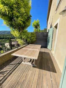 uma mesa de piquenique de madeira sentada num deque de madeira em Maison avec piscine à Lacoste em Lacoste