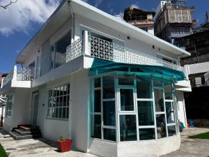 a white house with a balcony on top of it at The Warrick Homestay, A Luxe Stay Near Mall Road, Shimla in Shimla
