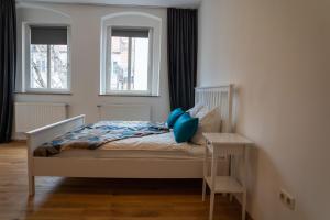 Schlafzimmer mit einem Bett mit blauen Kissen und einem Tisch in der Unterkunft Altstadtjuwel Liboria in Augsburg