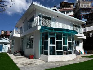 een wit huis met een groot raam en een balkon bij The Warrick Homestay, A Luxe Stay Near Mall Road, Shimla in Shimla