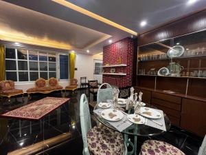 een eetkamer met tafels en stoelen en een kamer met ramen bij The Warrick Homestay, A Luxe Stay Near Mall Road, Shimla in Shimla