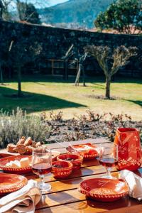 uma mesa de madeira com pratos vermelhos e taças de vinho em Just Like Home Casa do Rosmaninho em Caminha