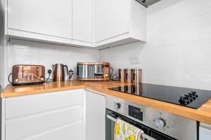 a kitchen with white cabinets and a stove top oven at I'm Your Host - Bridgeton House in Glasgow