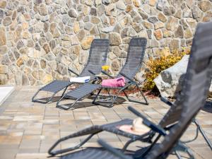 three chairs sitting in front of a stone wall at Villa Lemily in Matulji +41 photos