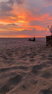 俊島的住宿－俊穆島陽光微笑海灘旅館，日落时坐在海滩上的人
