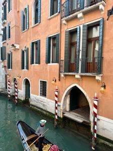 um homem numa gôndola num canal em frente a edifícios em Be Mate Ponte di Rialto em Veneza