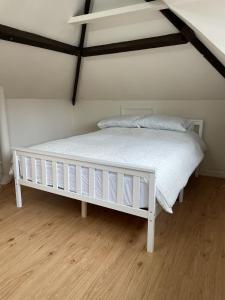 a white bed in a room with a wooden floor at The Corner House, 36, Broadway Road, in Evesham