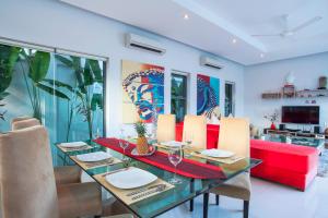 a dining room with a table and a red couch at Sumptuous Modern 3BR Pool Villa Mandala in Ban Saiyuan (1)