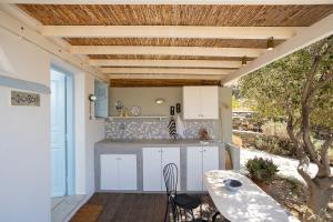 a kitchen with white cabinets and a table on a patio at Foivos suite at Serifos in Serifos Chora