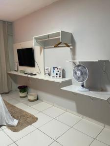 a room with a desk with a fan and a television at Flat JK 203 in Juazeiro do Norte
