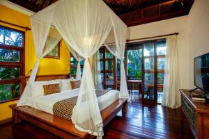 a bedroom with a bed with mosquito nets at Aryaswara Villa Ubud in Ubud