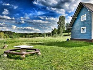 une table de pique-nique dans un champ à côté d'un bâtiment bleu dans l'établissement Czaplowisko - domki z sauną na Kaszubach, à Stare Czaple